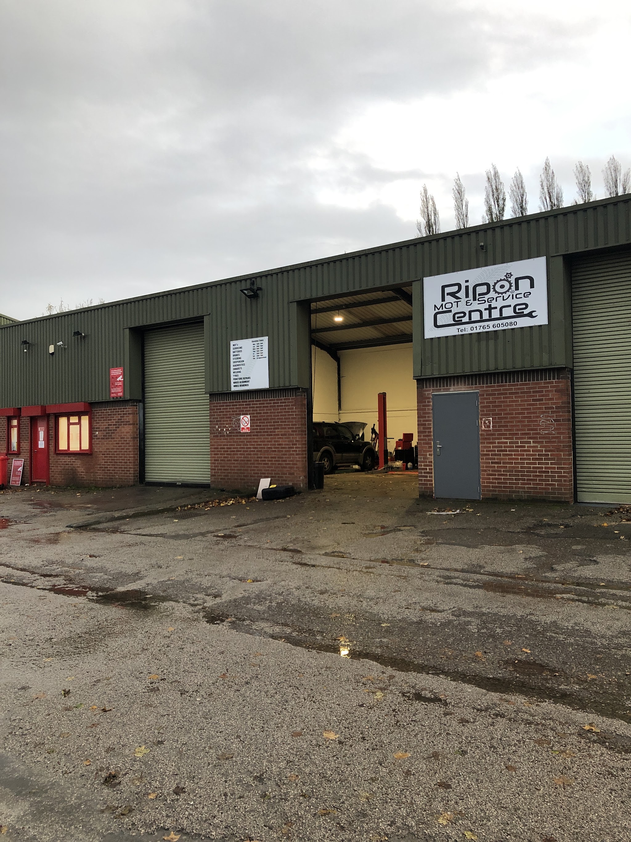 The front of the workshop, with our services board on the wall and a car up on the lift inside